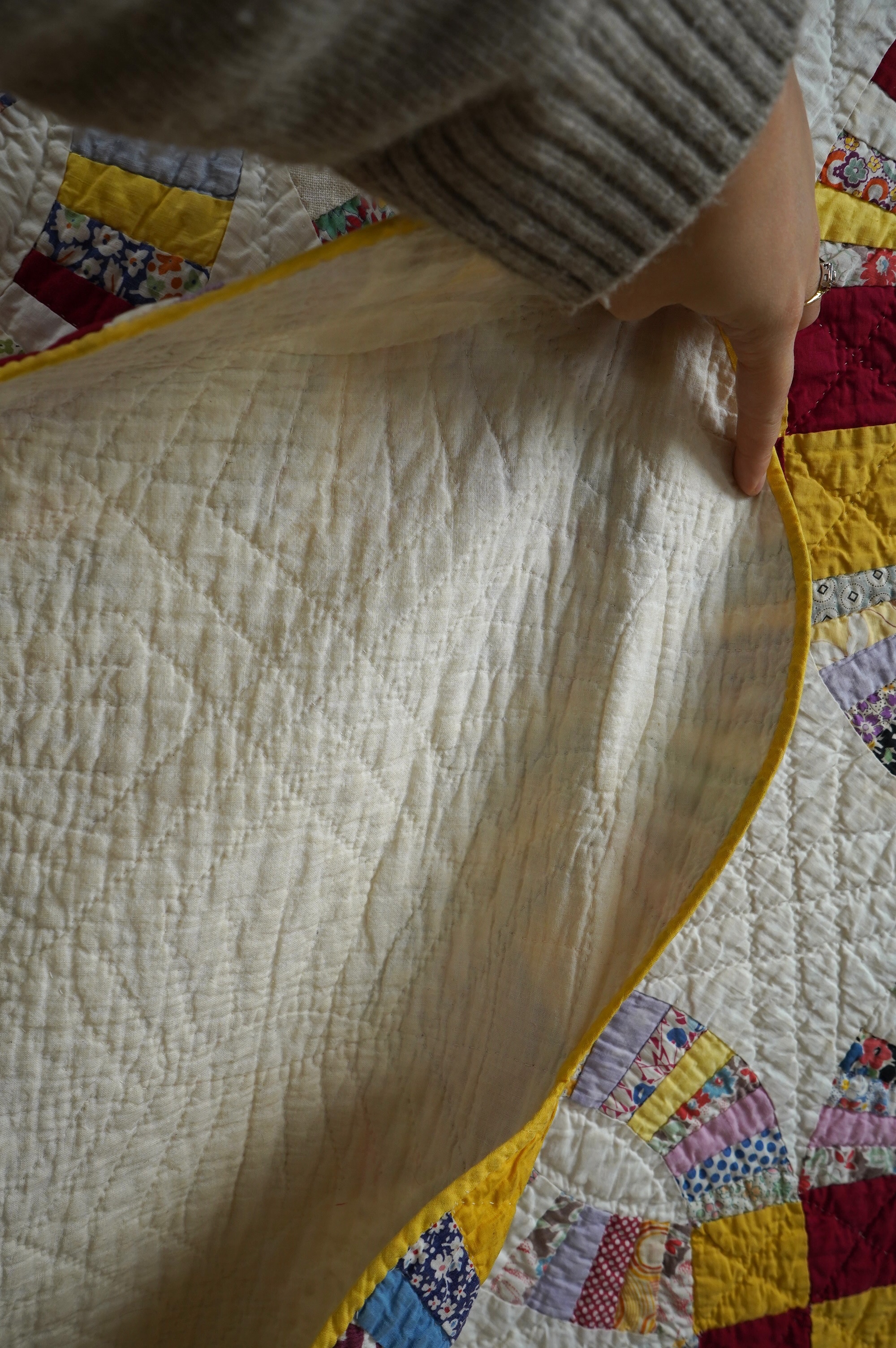 A 1940’s hand made ‘Double Wedding Ring’ patchwork quilt, made from bright multi-coloured floral and plain cotton dress fabrics into a patchwork design of large all over interlocking rings with a scalloped bright yellow